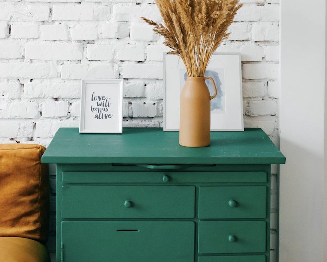 green drawers with vase and picture frame on top of it